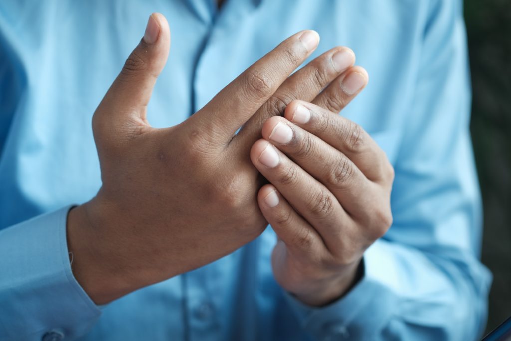 man feeling joint pain in fingers | Pledge to Fitness