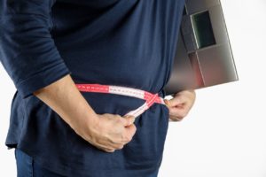 Sustainable Weight Loss - Pledge to Fitness |man holding scale measuring waist