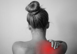 The back of a woman with a red area in her shoulder showing muscle soreness