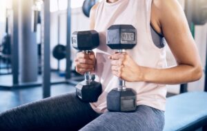 A woman performing a hypertrophy training exercise with a dumbbell at the gym.