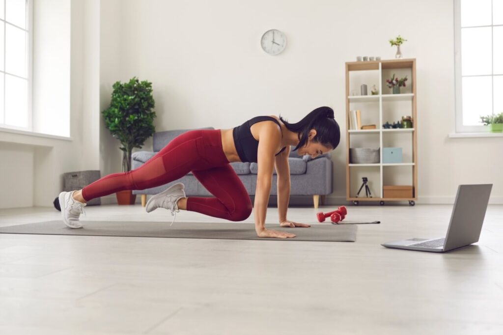 Woman working out at home, following an online personal training session.