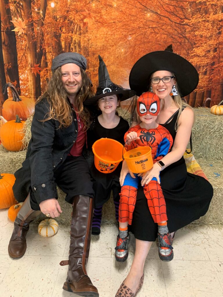 Elizabeth, her husband, and their children celebrating Halloween in festive costumes.