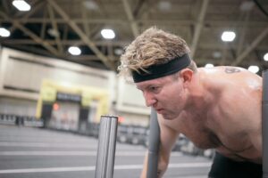 Man focused during an intense workout, pushing sled equipment indoors, representing the dedication and effort behind personalized fitness training.