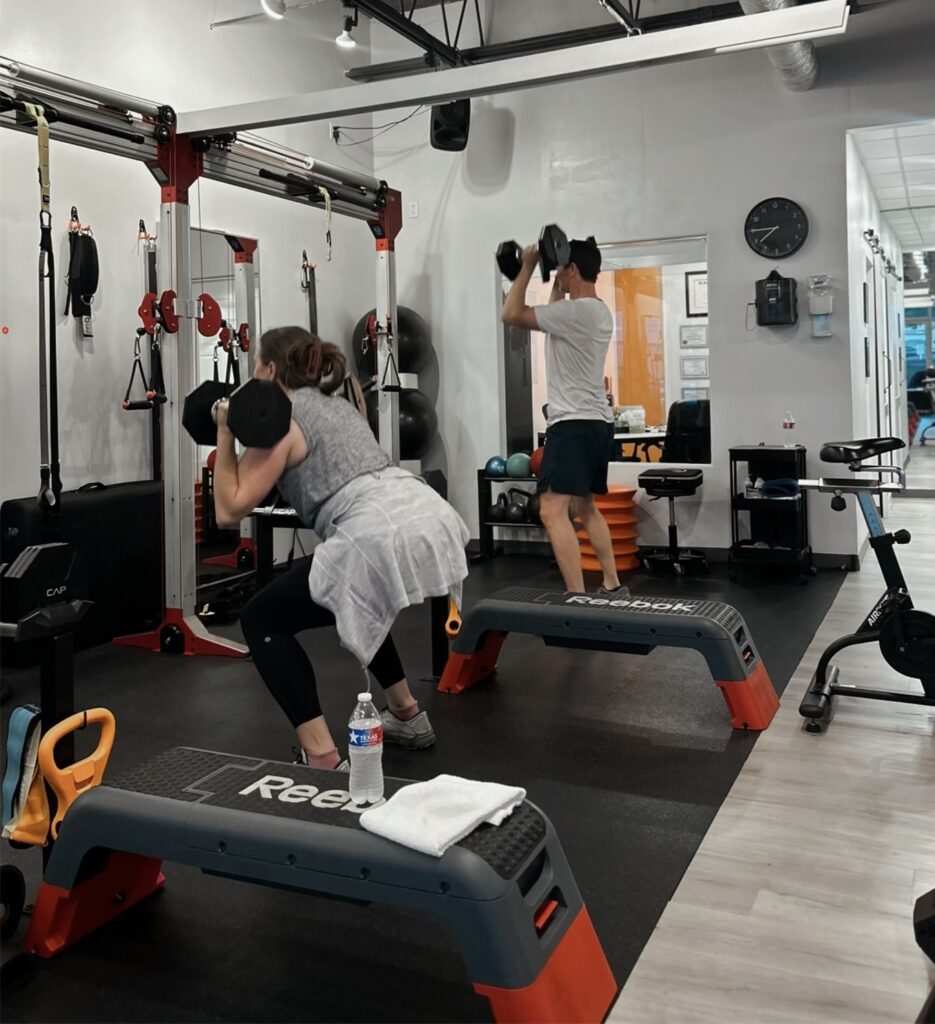 Couple doing dumbbell squats at Pledge To Fitness® Bellaire studio.