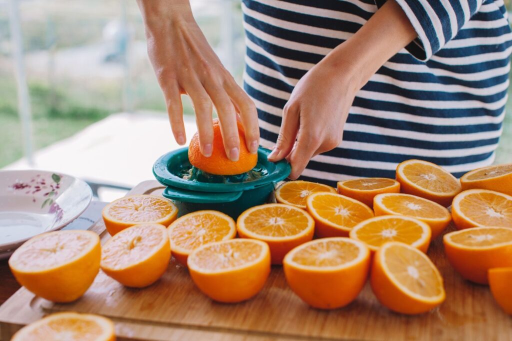Person squeezing fresh oranges to make juice, representing healthy nutrition and the importance of whole, nutrient-dense foods to support your training.