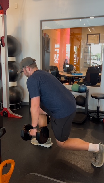 Dr. Collin Conrad performing a single-leg strength exercise with dumbbells during a personal training session at Pledge To Fitness.